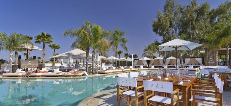 Luxurious poolside with cabanas and palm trees at Nikki Beach Marrakech.